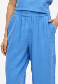 Lichtblauwe sweatpants van een textuur, ademende stof, met een elastische tailleband en zijzakken. Losse pasvorm.