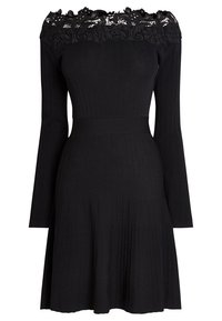 Robe noire côtelée avec un décolleté en dentelle Bardot, manches longues, corsage ajusté et jupe plissée évasée.