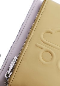 Bolsita de cuero amarilla y blanca con cierre de cremallera, que presenta un diseño en relieve y herrajes en color plata. Textura suave con detalle de costuras.