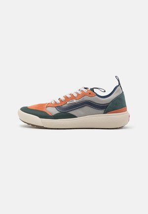 Zapatilla colorida que presenta paneles en naranja, gris, azul marino y verde, tejido texturizado, suela de goma y costuras reforzadas con cordones blancos.