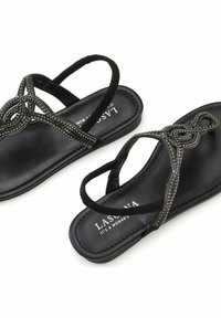 Black sandals with beaded accents, featuring a flat sole and crossed straps. Textured materials and decorative loops enhance the design.