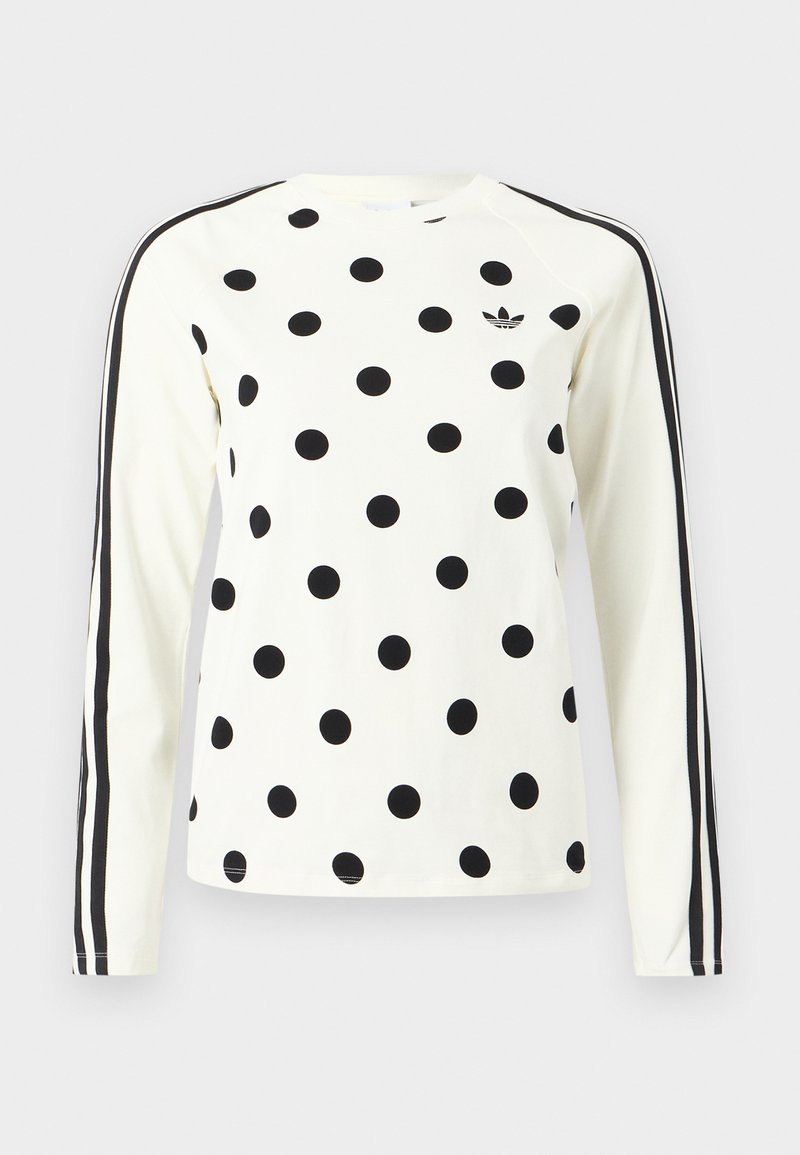 Hvid langærmet skjorte med sorte polkaprikker, sort Adidas-logo på brystet og to sorte striber, der løber ned ad hver ærme.