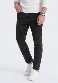 Svarta denim joggerbyxor med en åtsittande design, med sydda knädetaljer och en stretchig midja, i kombination med vita sneakers.