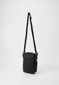 Bolso cruzado negro hecho de tela duradera; forma rectangular con correa ajustable, dos hebillas de metal y un bolsillo lateral con cremallera.