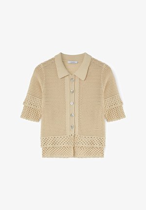 Beige gehaakte kortermige cardigan met kraag, knopen aan de voorkant en decoratieve opengewerkte patronen op mouwen en zoom.