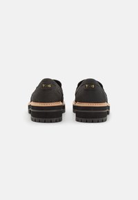 Mustad nahkadega muutest jalatsid paksema tallaga, millel on pruuni aksendiga riba, hammastega serv ja TOMS logo taga.