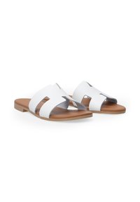 Sandales blanches à talon plat avec trois brides découpées, un semelage brun rembourré et une semelle extérieure beige. Matière supérieure en synthétique lisse.