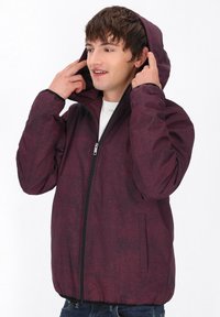 Burgundy pufferjacka med huva, prydd med ett rutmönster, framtill med dragkedja och sidofickor. Lätt material och elastiska ärmslut.