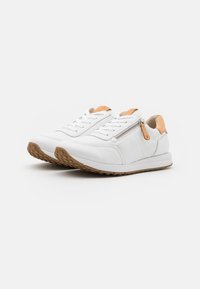 Baskets en cuir blanc avec un accent de fermeture éclair, talon beige et semelle en caoutchouc texturé. Lacets pour le maintien et un design élégant et arrondi.