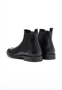 Botas Chelsea de cuero negro con paneles laterales elásticos y punteras redondas. Presentan una textura suave y un tacón bajo apilado.