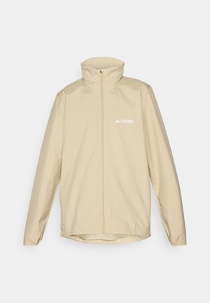 Beige leichte Jacke mit hohem Kragen, durchgehendem Reißverschluss und elastischen Bündchen; verfügt über ein kleines weißes Logo auf der linken Brust.