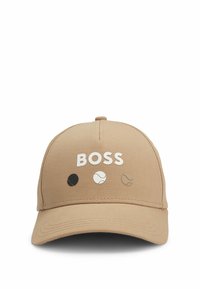 Cappellino da baseball color beige con il testo bianco "BOSS" e tre design di palline da tennis colorate (nero, bianco, beige) sul pannello anteriore. Texture liscia.