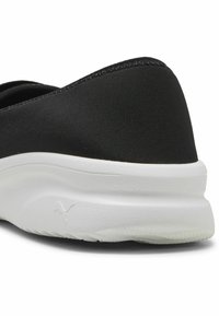 Fekete slip-on sneaker, amely textúrált felsőrésszel, rugalmas kialakítással és fehér gumitalppal rendelkezik, diszkrét márkajelzéssel.