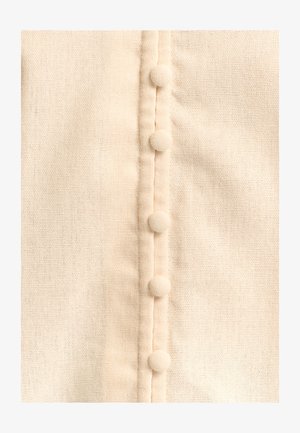 Cremefarvet stof med en tekstureret vævning, der har seks stofbetrukne knapper langs en central plade. Blød og glat udseende.