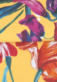 Textiel met levendige bloemmotieven in paars, rood en oranje op een gele achtergrond, met een subtiele stoftextuur.