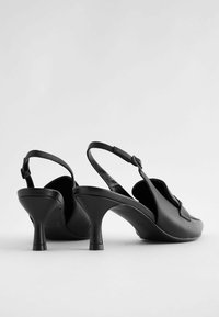Svarta slingback-klackar i slät läder med rundad tå, låg stilettklack och justerbar rem.