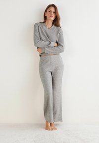 Conjunto de loungewear de punto gris que incluye una camiseta de manga larga acanalada con escote en V y pantalones de pierna ancha. La tela parece suave y tiene un ajuste relajado.