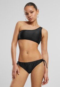 Black bikini set featuring a one-shoulder top and adjustable side-tie bottoms. Smooth, stretchy fabric with a matte finish.