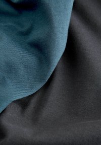 Two layers of fabric, one dark black and the other muted teal. Both have a smooth, slightly textured finish, creating a soft drape.
