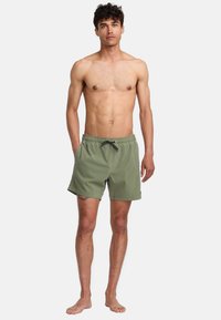 Shorts de bain vert olive avec une ceinture élastique et un cordon de serrage ajustable, dotés de poches latérales et d'un design simple.