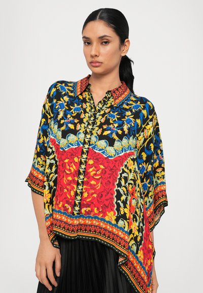 Colorful blouse featuring floral patterns in blue, yellow, and red on black fabric, with a patterned collar and loose, flowing design.