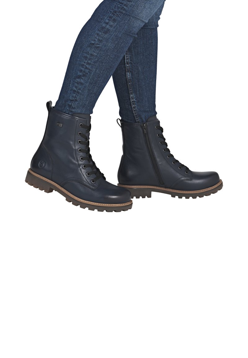 Dunkelblaues Leder-Ankle-Boots mit Schnürung vorne, seitlichem Reißverschluss, Gummisohle und tanfarbenen Akzenten; strukturierte Oberfläche mit robustem Design.