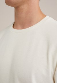 Texturált anyagból készült, off-white színű, kerek nyakú póló, rövid ujjal és szoros szabással.
