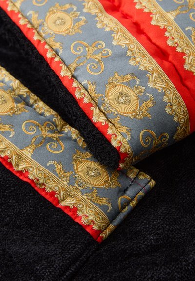 Črno teksturirano blago z okrasnim sivo-zlatnim vzorcem; obrobljeno z rdečim nagibom. Sijajni svilen videz na odtisanem delu.
