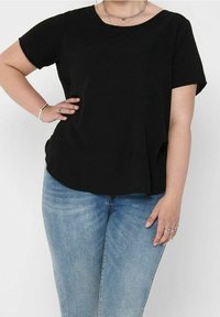 Haut noir à manches courtes avec un col rond et une coupe décontractée, associé à un jean bleu clair déchiré. Texture lisse, sans motifs visibles.