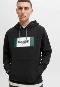 Schwarzer Hoodie aus weichem Stoff mit einer vorderen Kängurutasche, versehen mit einem weißen rechteckigen Grafikdesign und grünen Akzenten. Kordelzug an der Kapuze.