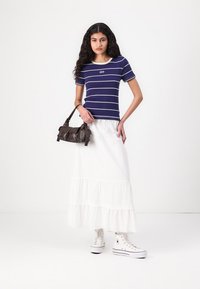 Marinbluse med striber og hvid kant, hvid lag-skørt, sort håndtaske og hvide høj-top sneakers. Hverdagsoutfit med tydelige mønstre.