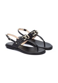 Sandalias de cuero negro con diseño de talón abierto, acentos en hardware dorado, suela plana y estilo de dedo del pie. Presentan una textura suave y un aspecto minimalista.