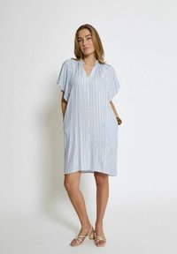 Gestreiftes Kleid mit V-Ausschnitt, kurzen, schwingenden Ärmeln und Seitentaschen. Aus leichtem Stoff in Blau und Weiß mit subtilen Details gefertigt.