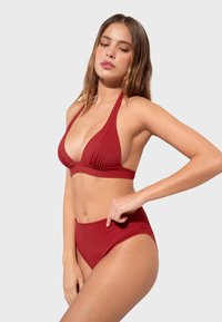 Rotes Bikini-Set mit einem Halterneck-Design, das eine tiefe V-Ausschnitt-Oberseite und hochgeschnittene Unterteile umfasst, aus glattem Stretchmaterial gefertigt.