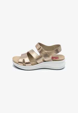 Sandalia metálica beige con puntera abierta, tres correas ajustables y una suela blanca acolchada y gruesa diseñada para comodidad y soporte.
