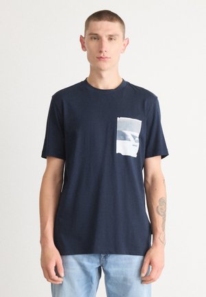 Tricou din bumbac de culoare bleumarin, cu mâneci scurte și un buzunar frontal, având un imprimeu grafic alb. Textură netedă, croi lejer.