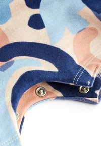Katoenen stof in een abstract patroon van blauw, perzik en beige, met metalen drukknoopsluitingen bij de kraag en een zachte textuur.
