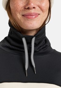 Zwarte sweater met hoge kraag van een textuurstof, met een wit en zwart visgraatkoord en een crème horizontale streep.