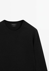 Maglione nero a maglia con scollo rotondo, caratterizzato da un colletto a coste, una texture morbida e un'etichetta che riporta il nome del marchio "Massimo Dutti."