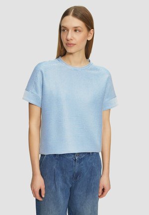 Haut à manches courtes bleu et blanc à rayures avec un col rond, offrant une coupe décontractée et une texture de tissu douce. Associé à un bas en denim.