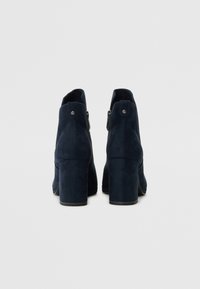 Tamno plave antilop čizme do članaka s blok petama, s patentnim zatvaračem sa strane i glatkom, mekom teksturom.