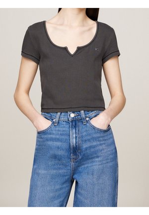 Un crop top côtelé gris foncé avec un décolleté en V et des manches courtes, associé à un jean en denim bleu taille haute avec une coupe classique.
