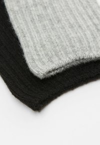 Dwie złożone kawałki tkaniny żebrowej w kolorze szarym i czarnym, ukazujące miękką teksturę, z widocznym wzorem dzianiny i gładkimi brzegami.