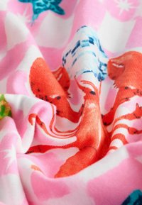 Bomullstyg med en livlig design av röda bläckfiskar och blå havsvarelser på en rosa och vit bakgrund med mjuk textur.