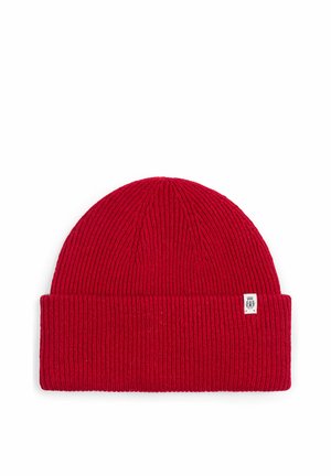 Red knitted beanie hat with folded brim and small white rectangular logo tag on the side.