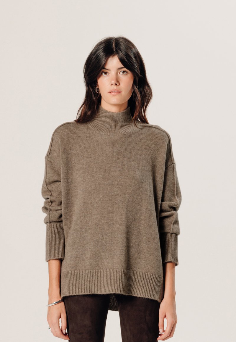 Übergrößen, olivgrüner Wollrollkragensweater mit gerippten Bündchen und Saum, präsentiert sich mit einer strukturierten Oberfläche und überschnittenen Schultern.