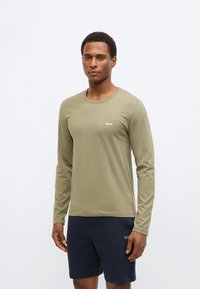 Long-sleeve olive green shirt with a crew neck and white "BOSS" logo, paired with navy shorts featuring a subtle texture.