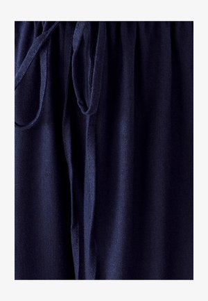 Granatowy materiał o miękkiej teksturze, z marszczoną talią i wiązanym detalem na sznurku. Gładki, lekki materiał.