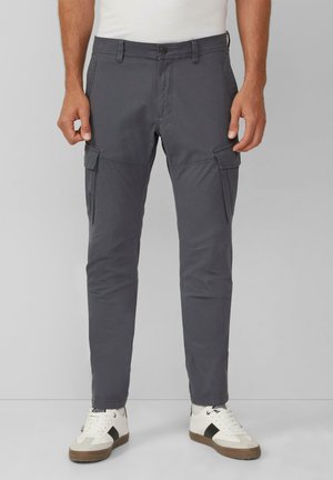Graue Cargo-Hosen mit zwei Seitentaschen, schlanker Schnitt und Gürtelschlaufen. Getragen mit weißen Sneakers, die schwarze Akzente und eine strukturierte Sohle haben.