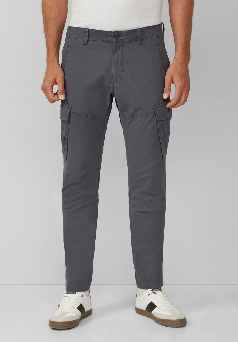Grijze cargobroek met twee zijzakken, slim fit en riemlussen. Gemaakt in combinatie met witte sneakers met zwarte accenten en een gestructureerde zool.